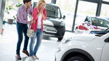 Man en vrouw kijken blij naar een witte auto.